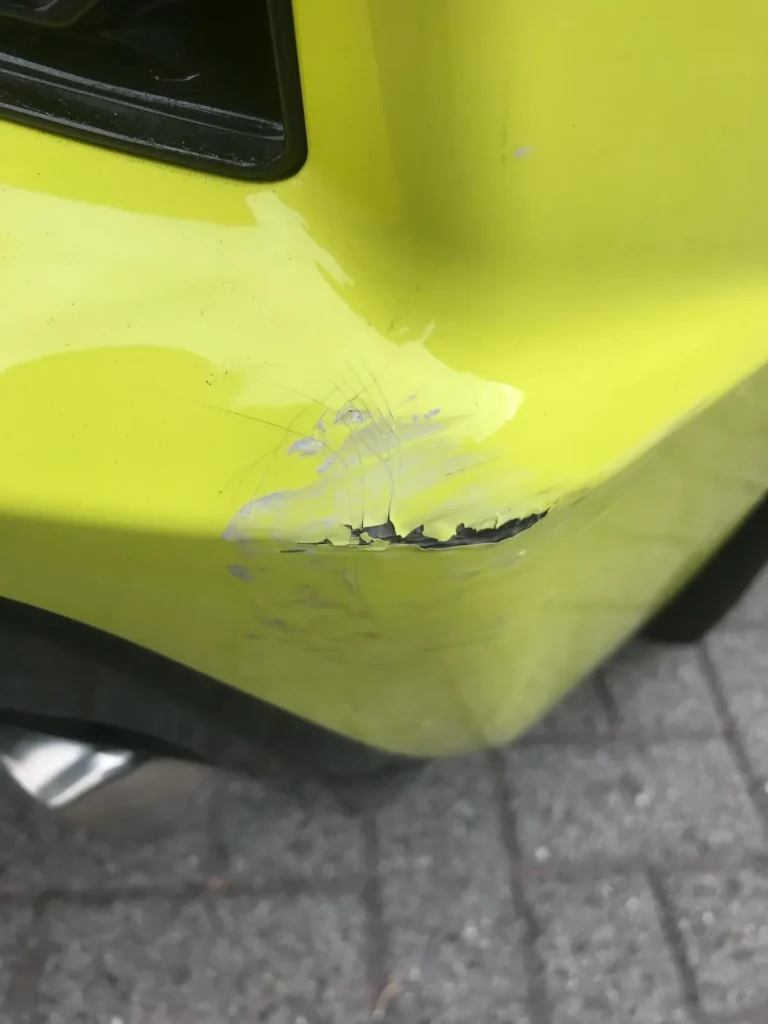 Gele sportwagen met schaafschade aan de achterbumper