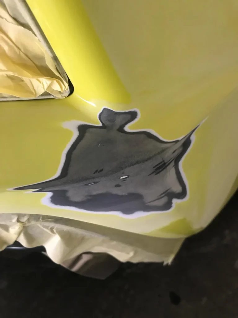 Geschuurde schadeplek op een gele bumper