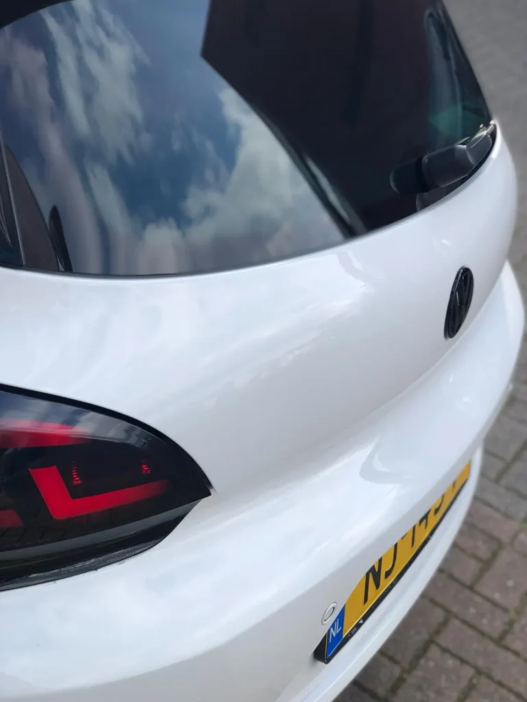 Witte hatchback na herstel van de deuk