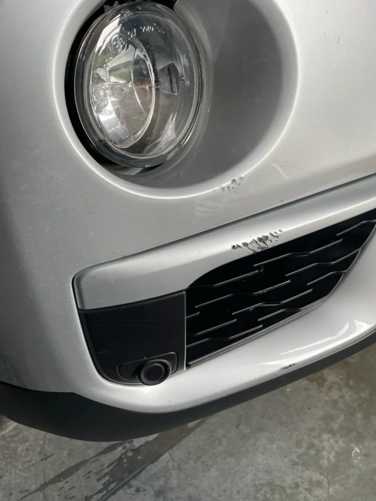 Zilveren auto met schaafschade aan de voorbumper